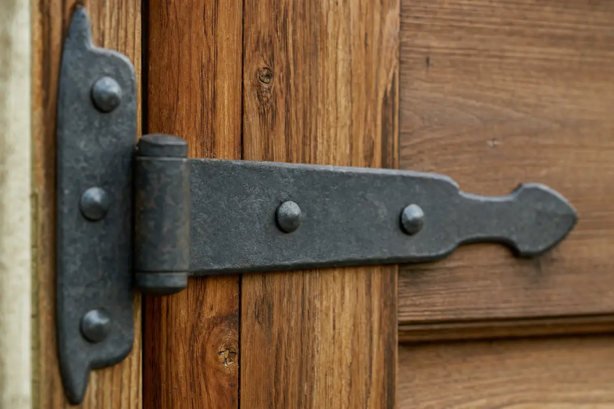 Close on the grain and joinery of a stained cedar garage door with an iron hinge